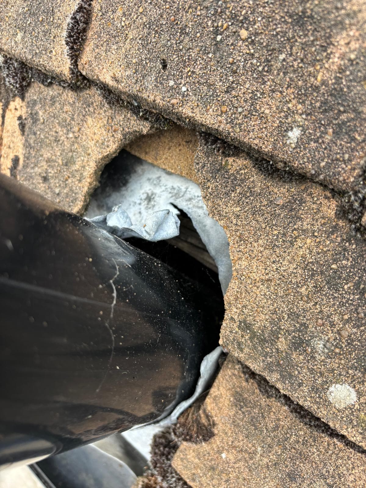 A pipe through a concrete tiled roof, where the tile round it has broken away
