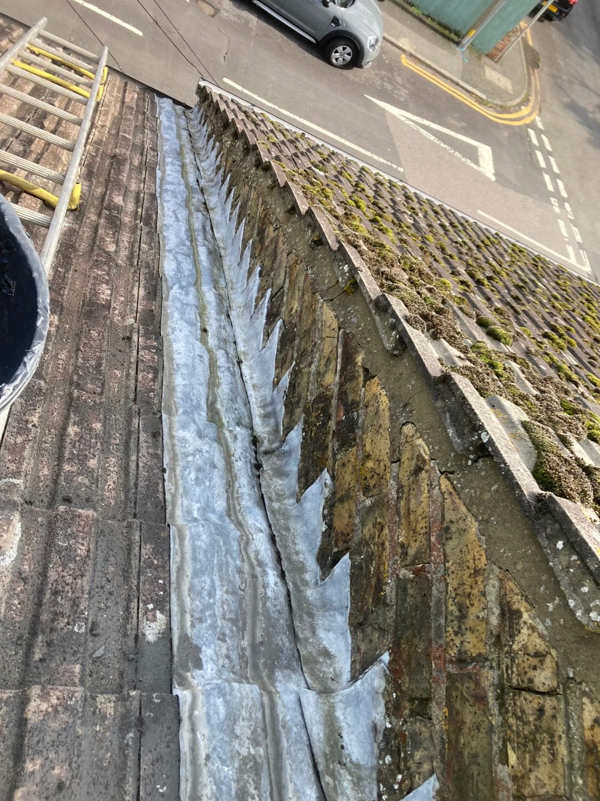 A lead lined gutter running between a tiled slope and a brick parapet
