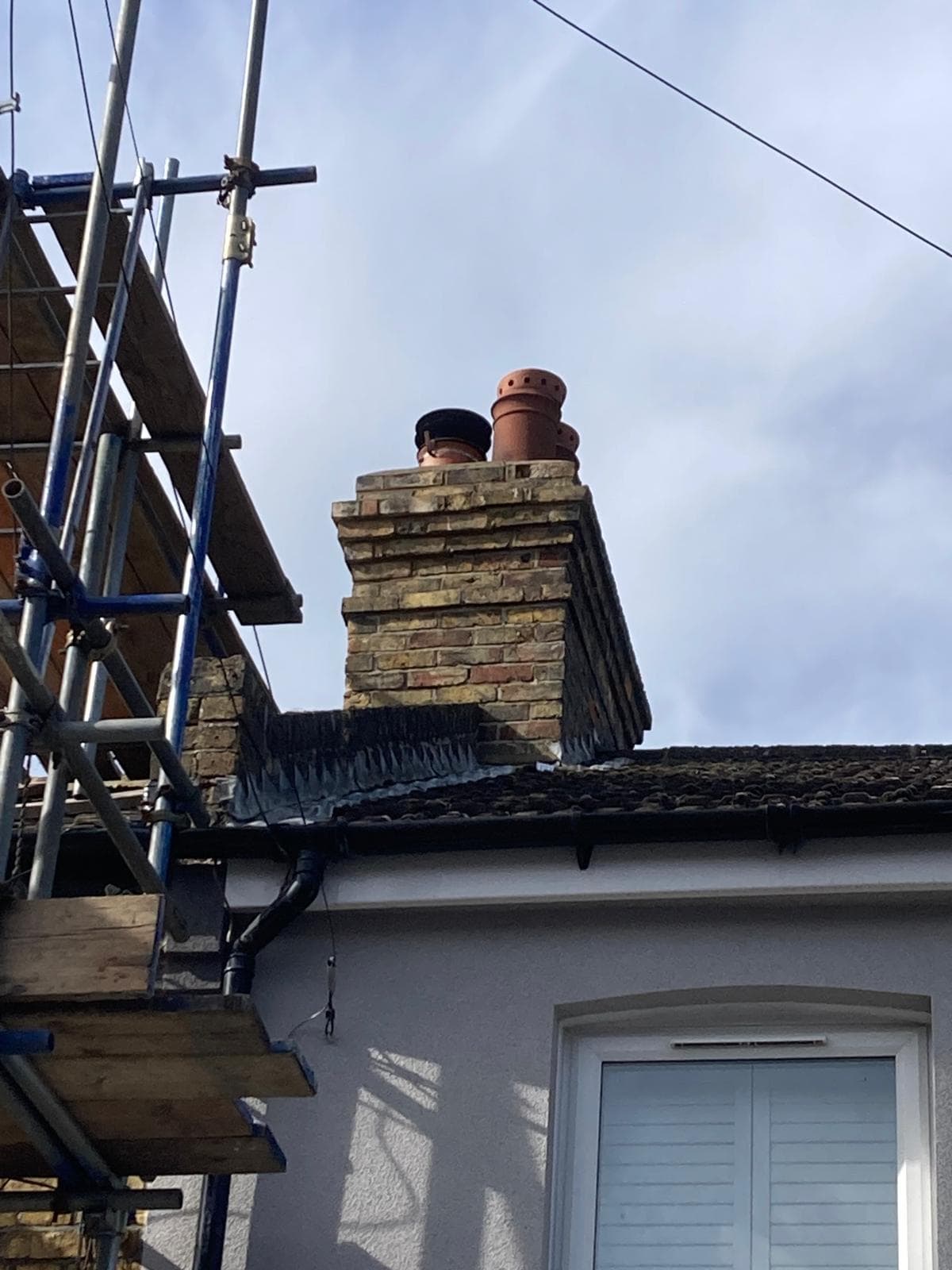 Fascia and gutter work on a rendered house in Hythe, with scaffolding up beside the chimney