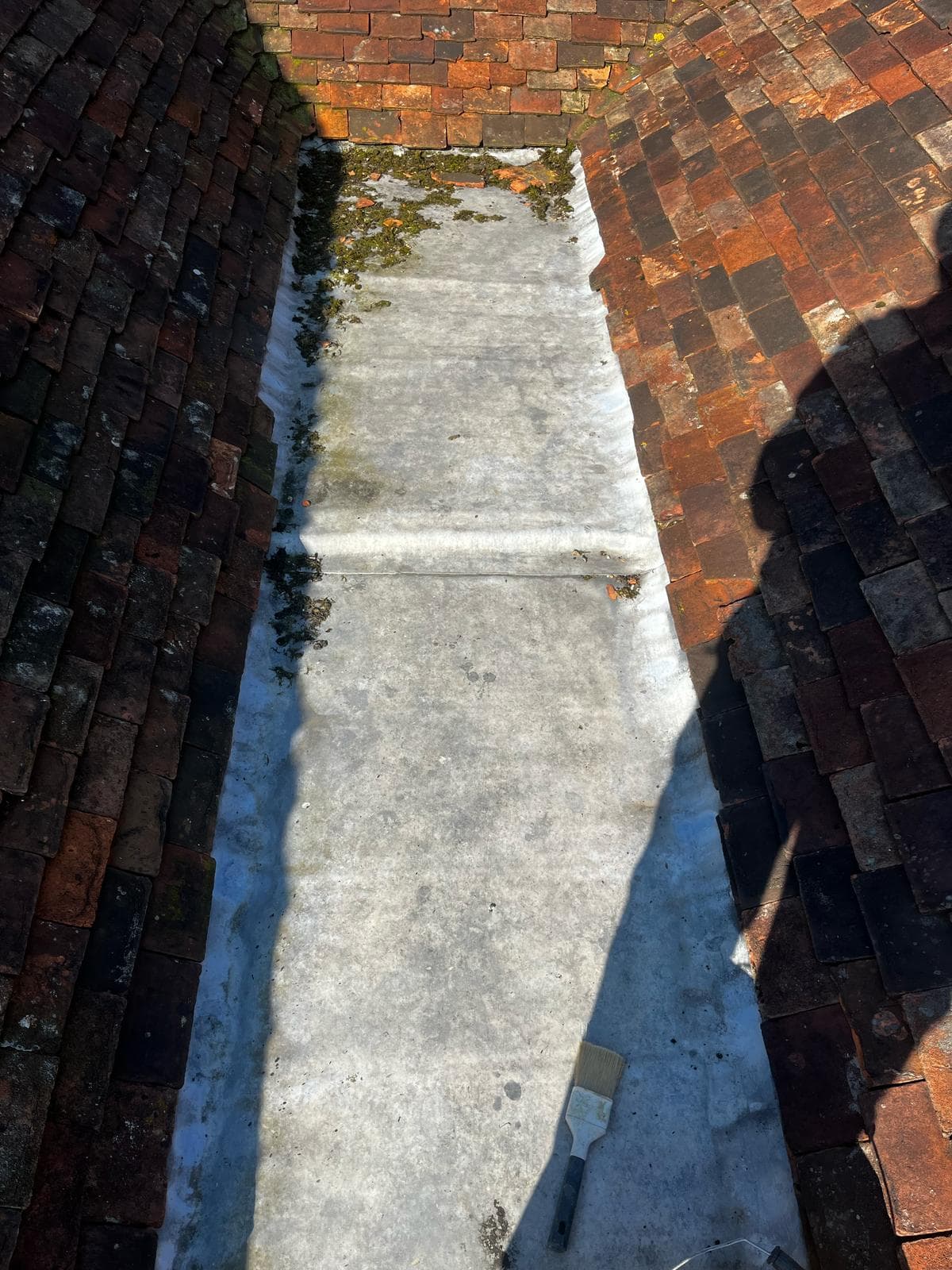 A lead lined gutter running between two clay tiled roof slopes