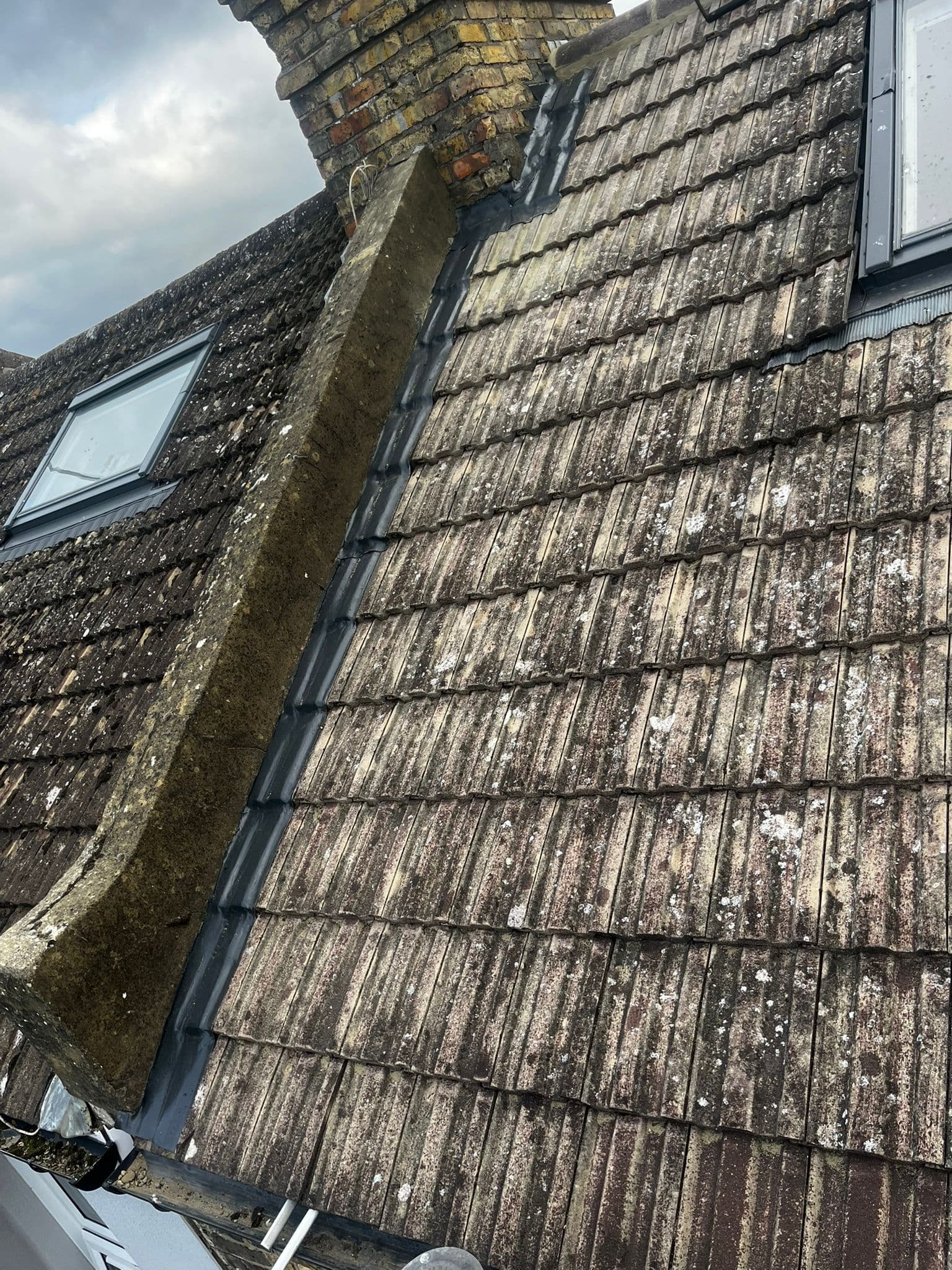 Roof windows in a concrete tiled slope, with a lead lined abutment beside them