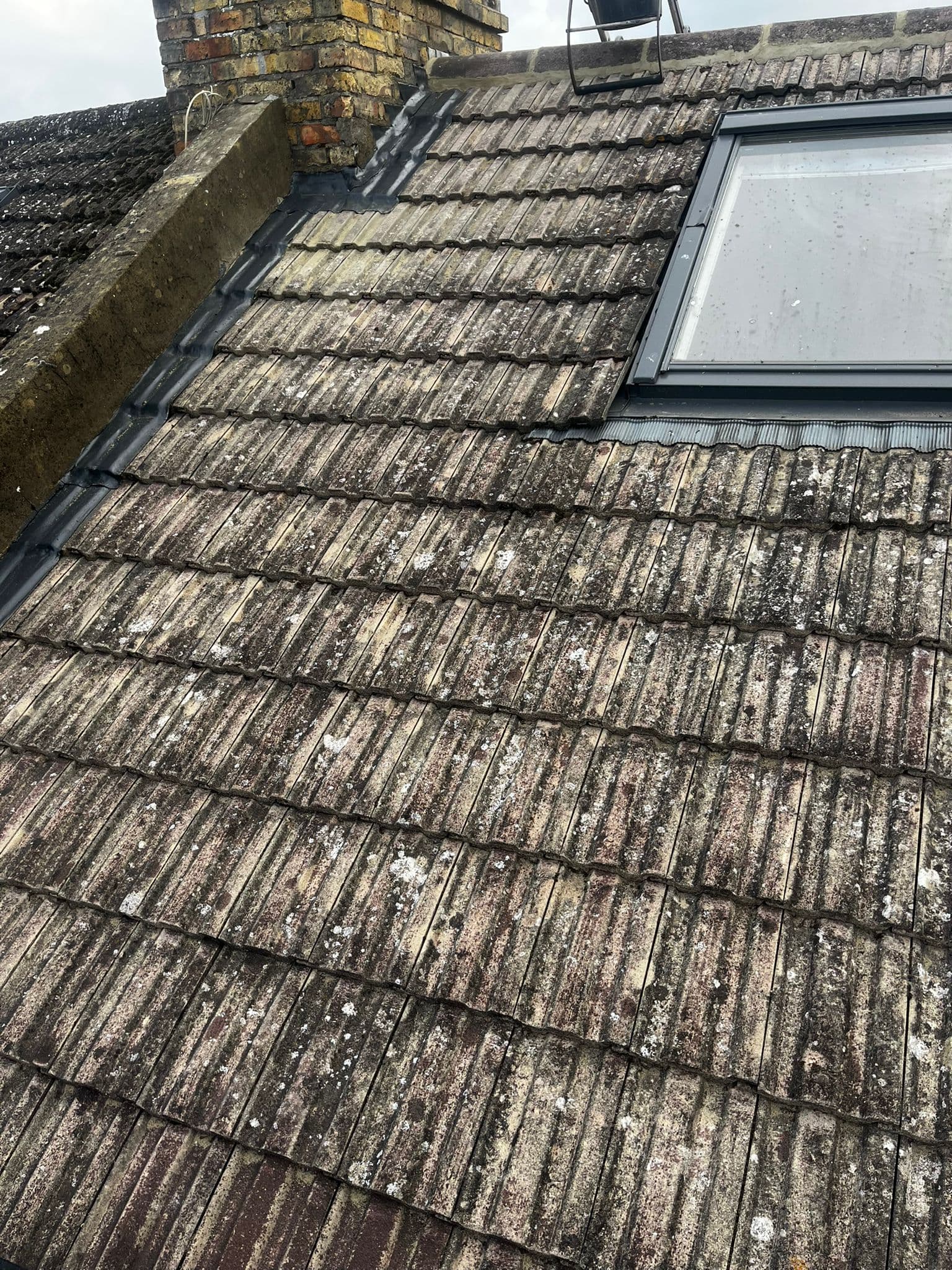 A roof window in a weathered concrete tiled slope