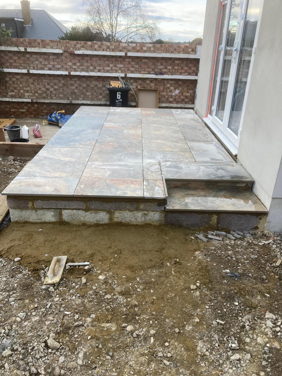 A newly laid stone effect patio with two steps up to the patio doors